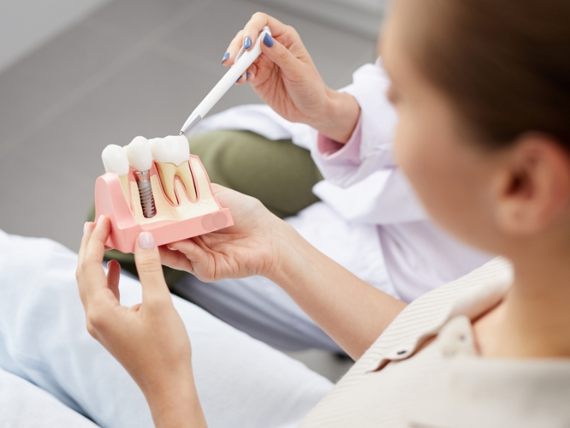 Patient learning from guide to dental implants with tooth model.